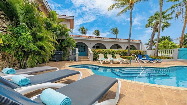 A poolside area with lounge chairs, a swimming pool, and tropical vegetation.