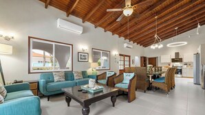 A spacious living area with a high ceiling, wooden beams, and a central seating arrangement.