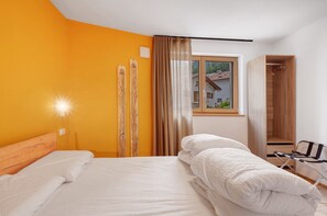 Une chambre d’hôtel avec un lit, une armoire en bois et une fenêtre donnant sur une maison.