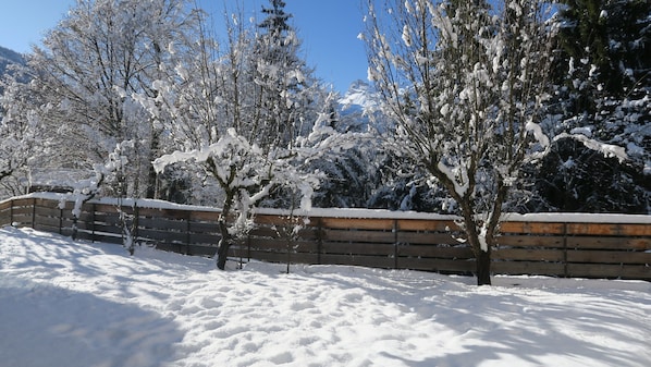 A snow-covered landscape with trees and a wooden fence.
