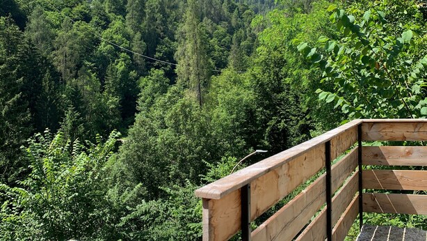 A wooden bench with a metal frame, overlooking a forested valley with mountains in the background. - Apartment 'Bruna' with Mountain View, Private Terrace and Wi-Fi (Forno di Zoldo)