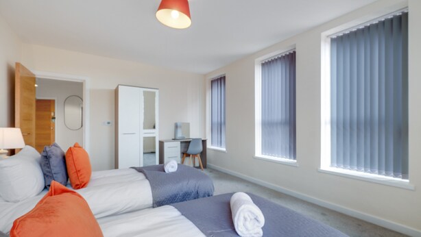 Una habitación de hotel moderna con dos camas, un escritorio y una silla.