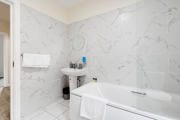 A bathroom with a bathtub, a sink, and a mirror.