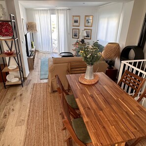 Un comedor con mesa de madera, sillas, un sofá y un jarrón de flores.