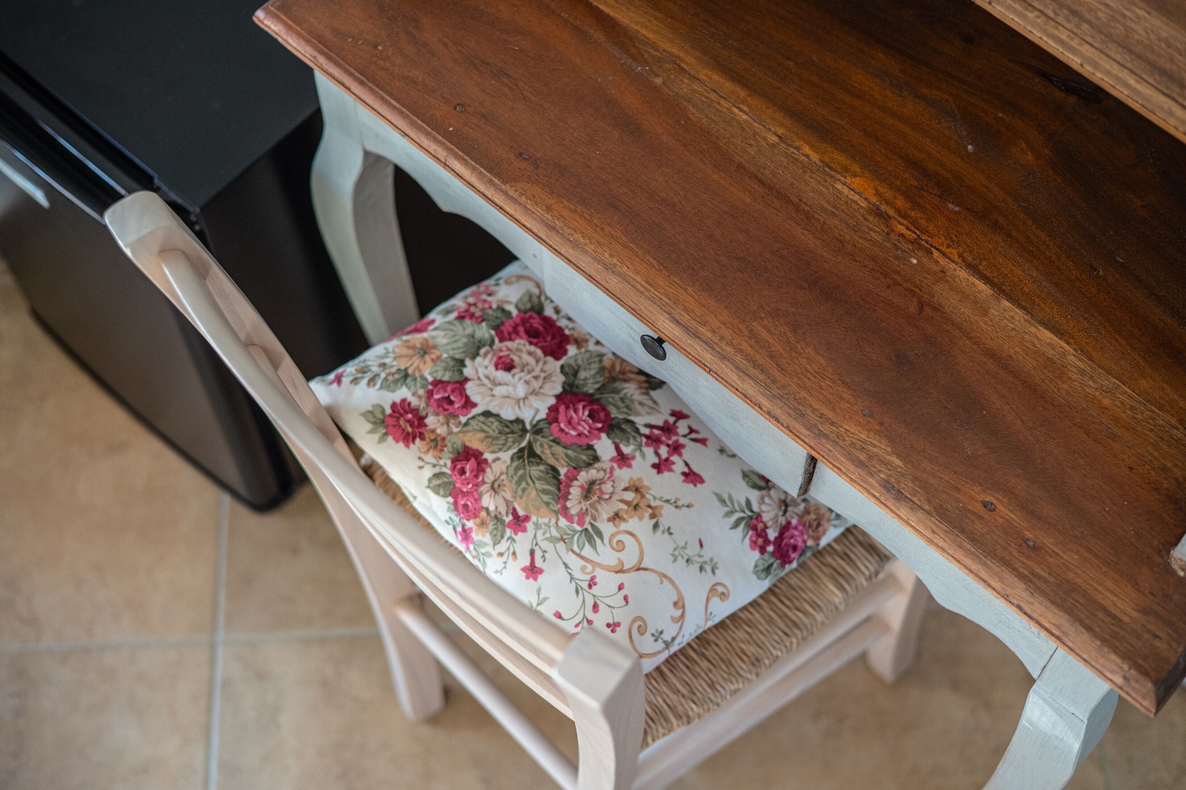 Une table en bois avec un coussin à motifs floraux sur une chaise.