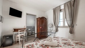 A bedroom with a bed, a desk, a chair, a wardrobe, a TV, and a window with curtains. - Room 'Giusti - 4 Querce' with Shared Garden, Wi-Fi and Air Conditioning (Magliano in Toscana)