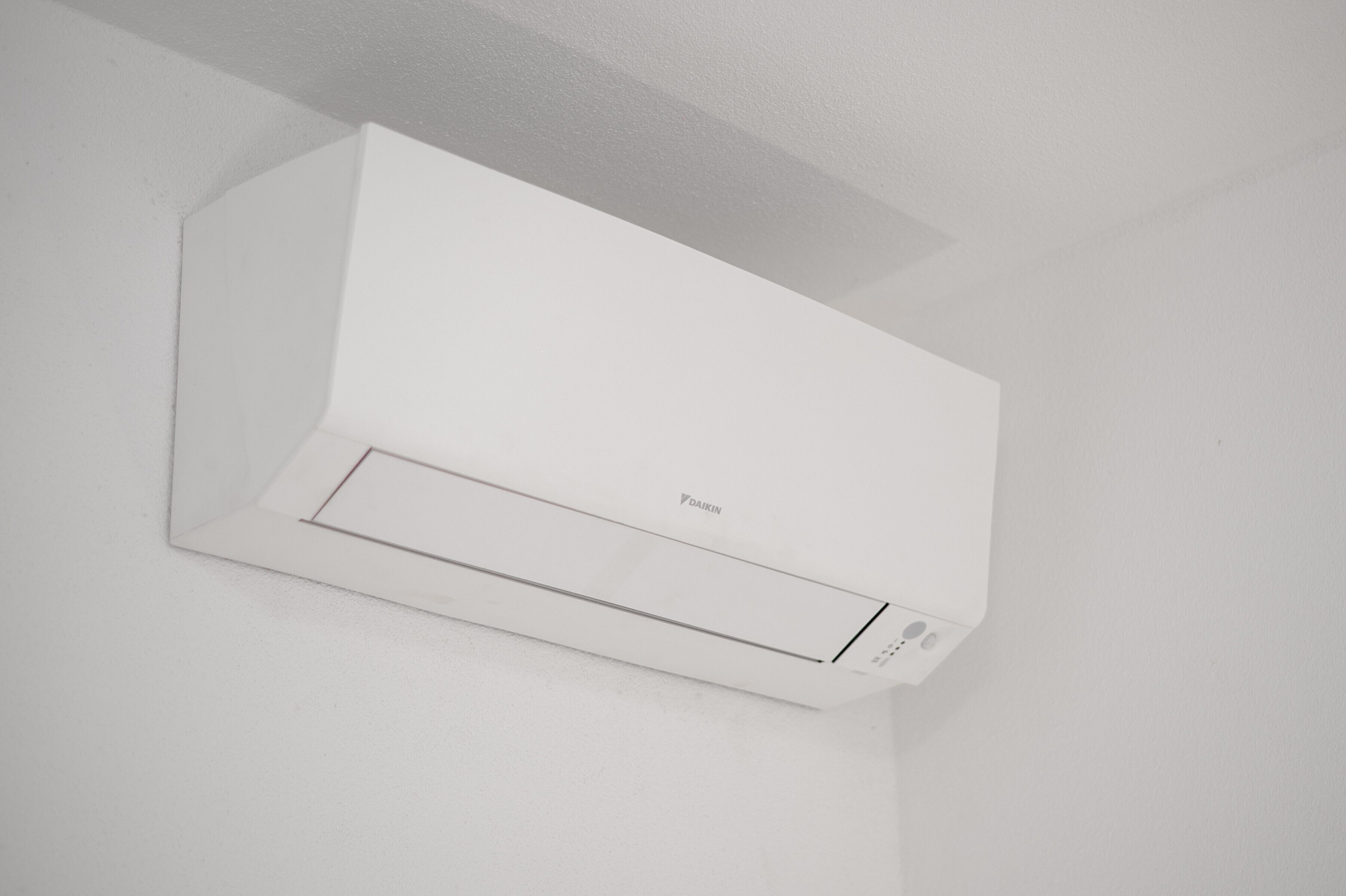 Un appareil de climatisation blanc, fixé au mur, doté d’un panneau de commande et d’une marque visible.