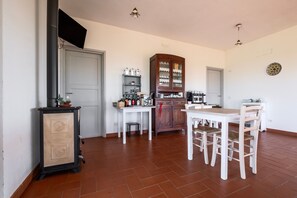 Une cuisine équipée d’une table et de chaises, d’un meuble de rangement et d’un téléviseur fixé au mur.