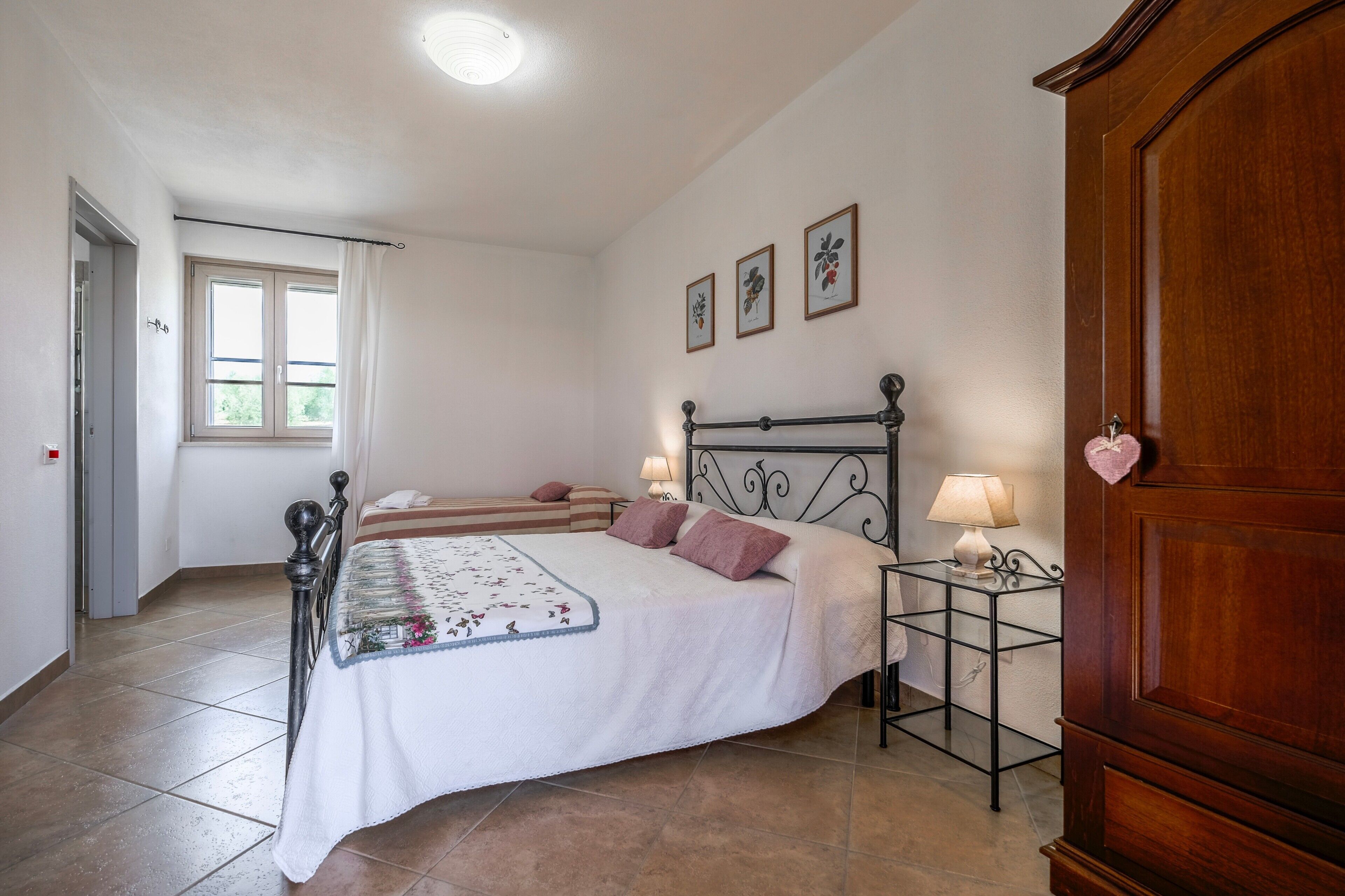 Un dormitorio con cama, mesitas de noche, armario y ventana.