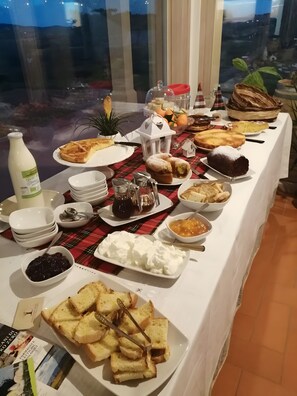 Een buffet met diverse gerechten, waaronder gebak, brood en toevoegingen.