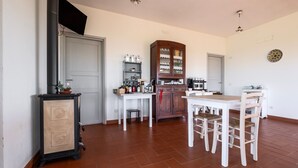 Eine Küche mit Esstisch und Stühlen, einem Schrank und einem an der Wand befestigten Fernseher.