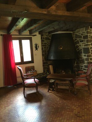 A rustic interior with a stone fireplace, wooden furniture, and a red curtain.