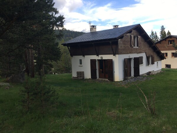 A rustic wooden house with a sloped roof, a small porch, and a chimney.