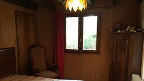 A wooden room with a bed, a chair, a window, and a cabinet. - Chalet 'Les Iris' with Mountain View and Private Garden (Unknown)
