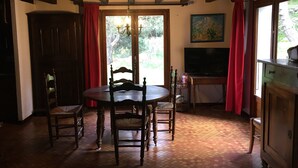A dining area with a wooden table and chairs, a television, and a painting on the wall. - Chalet 'Les Iris' with Mountain View and Private Garden (Unknown)