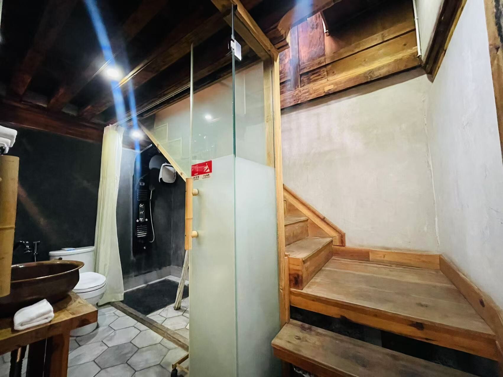 Une salle de bain avec un banc en bois, une cloison en verre et un panneau rouge indiquant la sortie de secours.