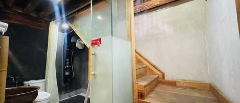 Une salle de bain avec un banc en bois, une cloison en verre et un panneau rouge indiquant la sortie de secours.