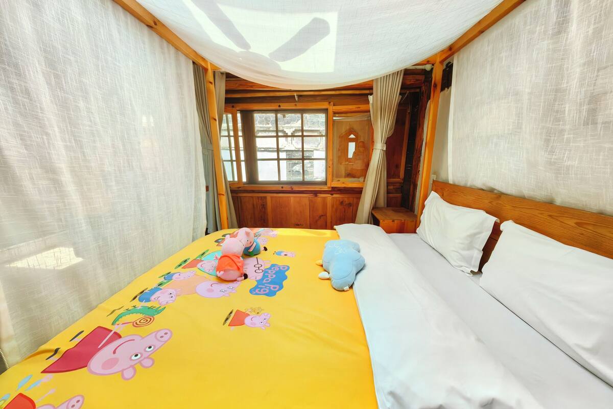 Ein Zimmer mit einem Bett, einem Fenster und Vorhängen.