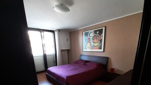 Een slaapkamer met een bed, een schilderij aan de muur en een raam.