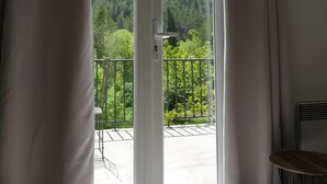 A room with a sliding glass door leading to a balcony with a view of a forested hillside. - Holiday Home 'Gabriel' with Mountain View, Private Terrace and Wi-Fi (Buis-les-Baronnies)