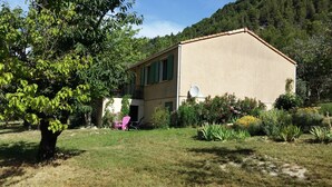 A two-story building with a flat roof, surrounded by a well-maintained garden with various plants and flowers. - Holiday Home 'Gabriel' with Mountain View, Private Terrace and Wi-Fi (Buis-les-Baronnies)
