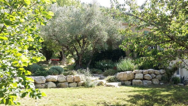 A garden with a stone wall, various shrubs, and trees. - Holiday Home 'Gabriel' with Mountain View, Private Terrace and Wi-Fi (Buis-les-Baronnies)