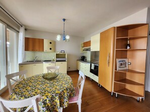 A compact kitchen with a dining table, chairs, a chandelier, and wooden cabinets.