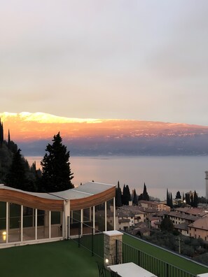 A modern building with a glass facade, a green roof, and a view of a lake and distant mountains. - Apartment 'Alba Lake View   Pool' with Lake View, Shared Pool and Air Conditioning (Toscolano Maderno)