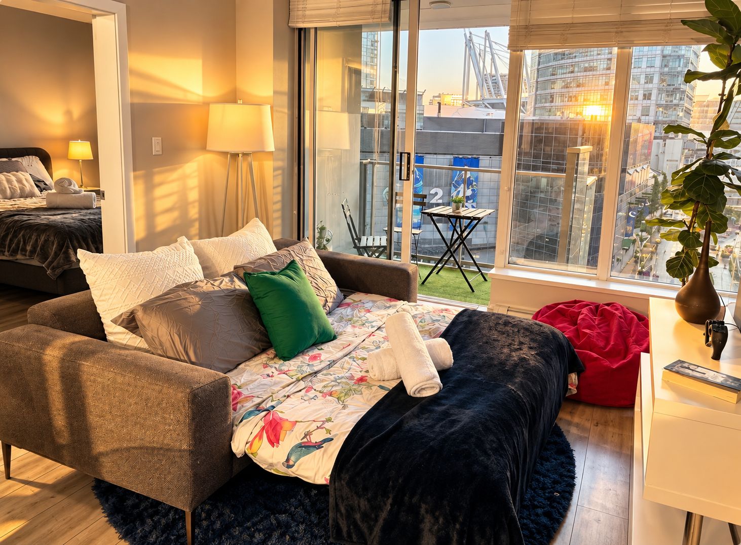 A modern living room with a sofa, a coffee table, and a view of a cityscape through large windows.
