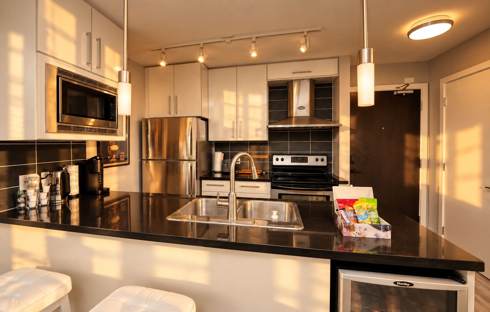 A modern kitchen with stainless steel appliances, a black countertop, and a built-in oven.
