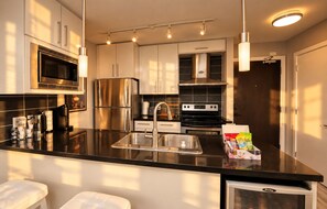 Una cocina moderna con electrodomésticos de acero inoxidable, encimera negra y horno integrado.