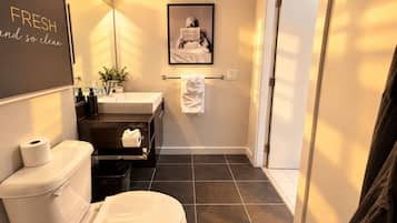 A modern bathroom with a toilet, sink, and a framed picture on the wall.