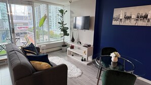 Ein modernes Wohnzimmer mit einem grauen Sofa, einem Glastisch und einer blauen Akzentwand.