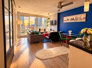A modern living room with a city view, a dining area, and a large window. - New 2025 Luxury Stadium views/Downtown Core (Vancouver)