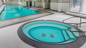 Ein Hallenbad mit klarem Wasser, gefliestem Boden und einer Sicherheitsreling.