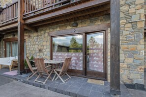 Ein Steinhaus mit Balkon, Holzmöbeln und einem großen Fenster.