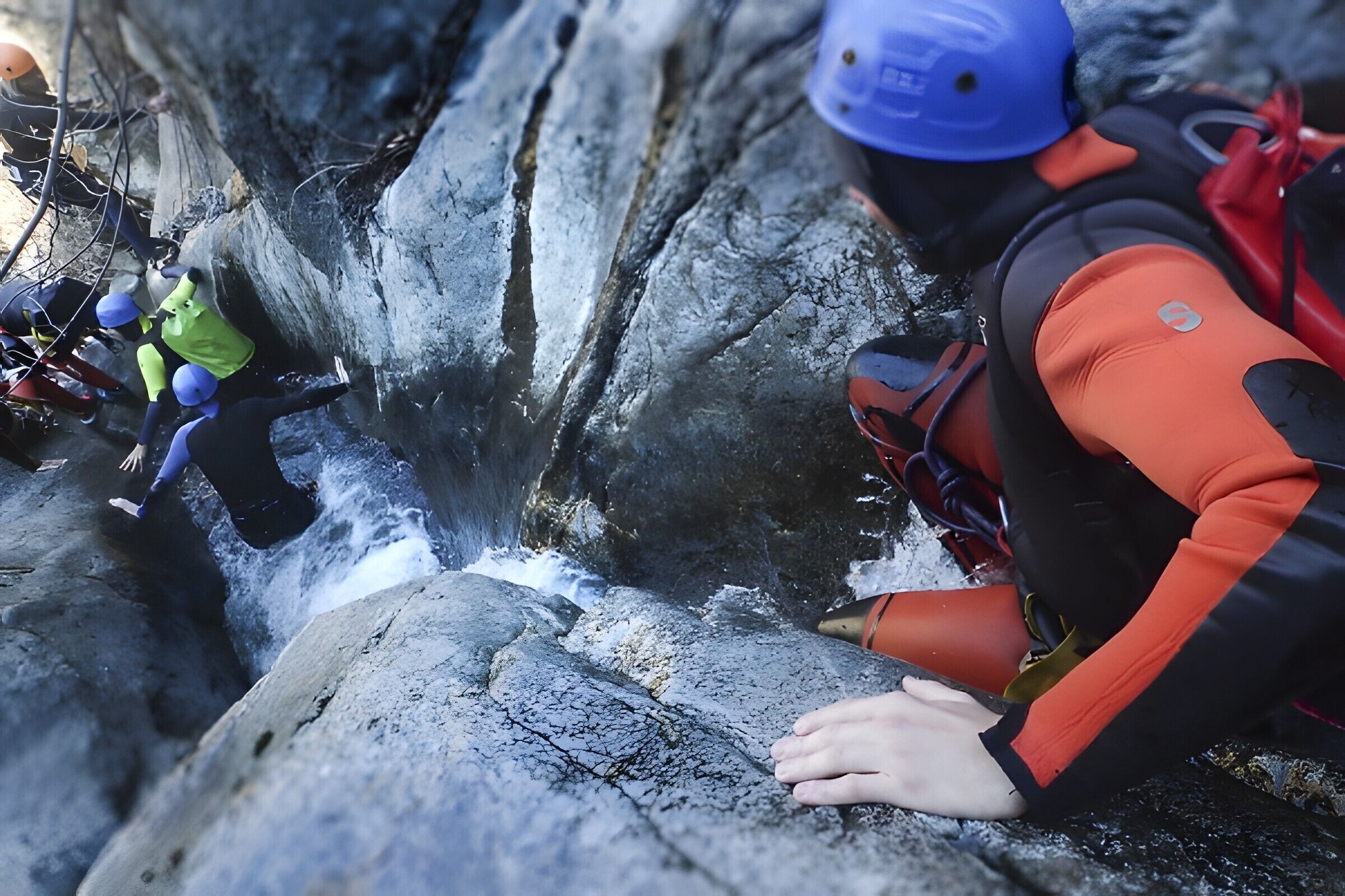 Una persona descendiendo en rappel por un risco rocoso.