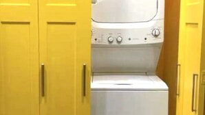 A laundry room with a washing machine and dryer, enclosed by yellow doors.