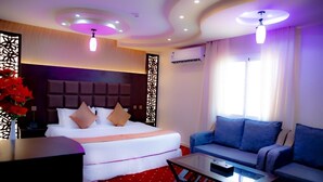 A hotel room with a bed, a sofa, a coffee table, and a decorative wall panel. - Alsultan Inn Hotel (Jizan)