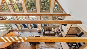 A high-ceilinged room with a wooden beam structure, a seating area with a sofa and chairs, and a dining table. - Peaceful Cabin with Epic Mountain Views! (Florissant)