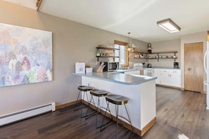 Une cuisine moderne dotée d’un îlot central, de tabourets de bar et d’un grand tableau abstrait accroché au mur.