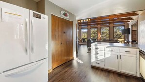 A modern kitchen with a built-in refrigerator, wooden cabinets, and a large window overlooking a scenic view. - Peaceful Cabin with Epic Mountain Views! (Florissant)