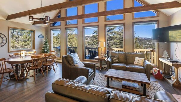 A spacious living area with a high ceiling, large windows, and a cozy seating arrangement. - Peaceful Cabin with Epic Mountain Views! (Florissant)
