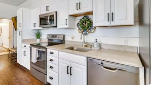 A modern kitchen with white cabinets, stainless steel appliances, and a decorative wreath. - Historic New Market Retreat w/Washer and Dryer (New Market)