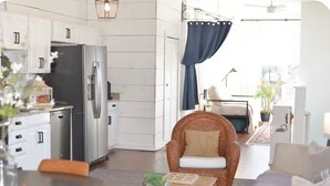 A modern kitchen with white cabinets, a stainless steel refrigerator, and a dining area with a wooden table and wicker chair. - Historic New Market Retreat w/Washer and Dryer (New Market)