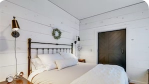 A bedroom with a bed, bedside tables, a wall-mounted lamp, and a door. - Historic New Market Retreat w/Washer and Dryer (New Market)