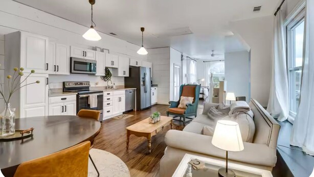 A modern kitchen with white cabinets, a dining table, and a sofa in the living area. - Historic New Market Retreat w/Washer and Dryer (New Market)