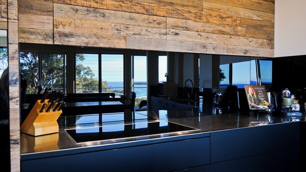Una cucina moderna con una grande finestra, un soffitto in legno e vista sul mare.