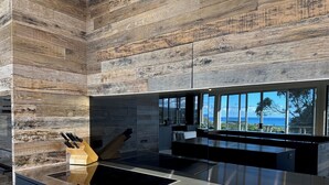 Una cucina moderna con una grande isola, elettrodomestici in acciaio inossidabile e vista sull'oceano.