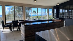Una cucina moderna con ampie finestre, un'isola in legno e vista sull'oceano.